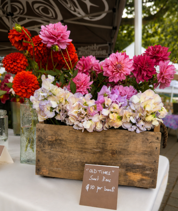 A wooden crate of sweet peas and dahlias at the farmers market